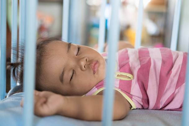 Baby girl is sleeping in baby cot. - Photo, Image