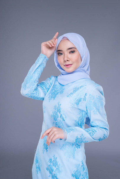 Modelo feminino muçulmano bonito vestindo azul pastel moderno kurung com hijab, um vestuário de estilo de vida urbano para mulheres muçulmanas isoladas em fundo cinza. Beleza e hijab conceito de moda. Metade do comprimento
 - Foto, Imagem