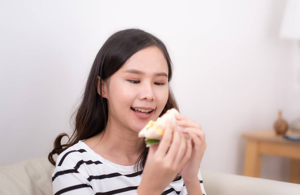 Молода азіатка їсть бутерброд удома.. - Фото, зображення