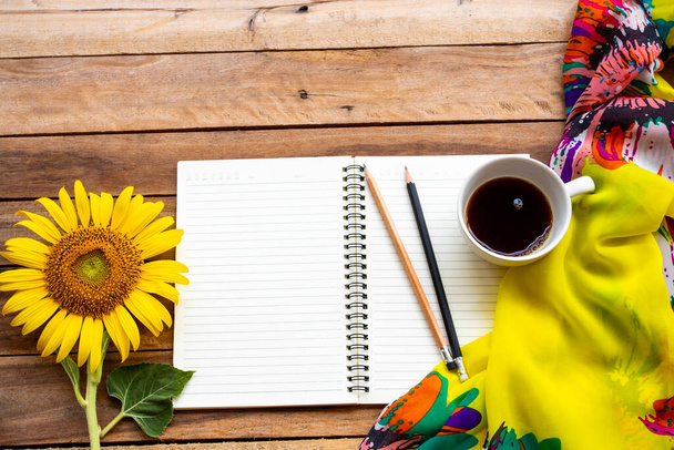 Планувальник ноутбуків для бізнесу для роботи з гарячою кавою, жовтими квітами соняшник, розташування шкарпеток плоский стиль на фоні дерев'яного
 - Фото, зображення