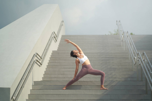podążając za trendem uprawiania jogi na otwartych przestrzeniach, azjatycka Chinka uprawia jogę na schodach - Zdjęcie, obraz