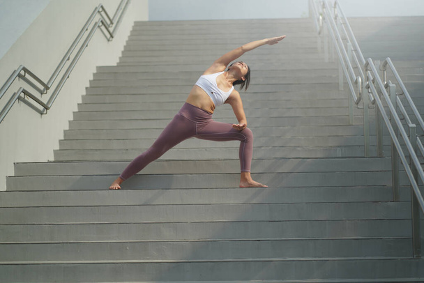 dem Trend folgend, Yoga im öffentlichen Raum zu machen, asiatische Chinesin macht Yoga auf Treppen - Foto, Bild