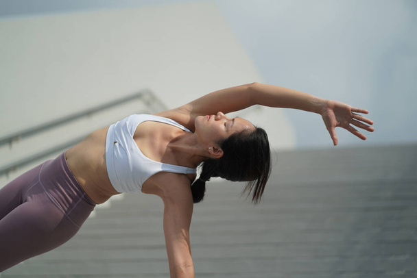seguindo a tendência de fazer ioga em espaços abertos públicos, senhora chinesa asiática fazendo Yoga em escadas
 - Foto, Imagem