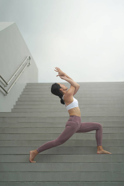 siguiendo la tendencia de hacer yoga en espacios públicos abiertos, asiática china dama haciendo yoga en escaleras
 - Foto, Imagen