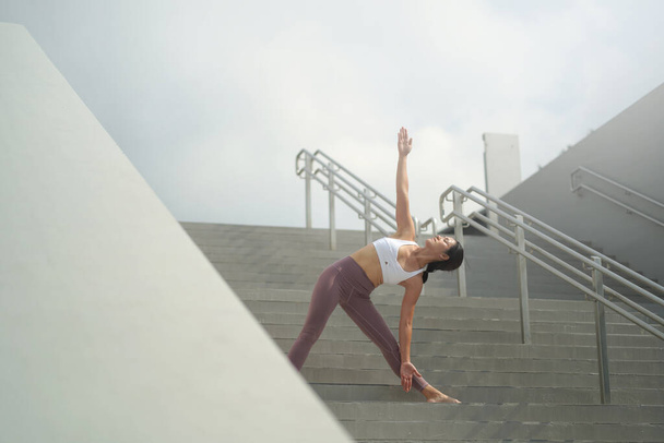 seguendo la tendenza di fare yoga in spazi aperti pubblici, signora cinese asiatica che fa Yoga sulle scale
 - Foto, immagini