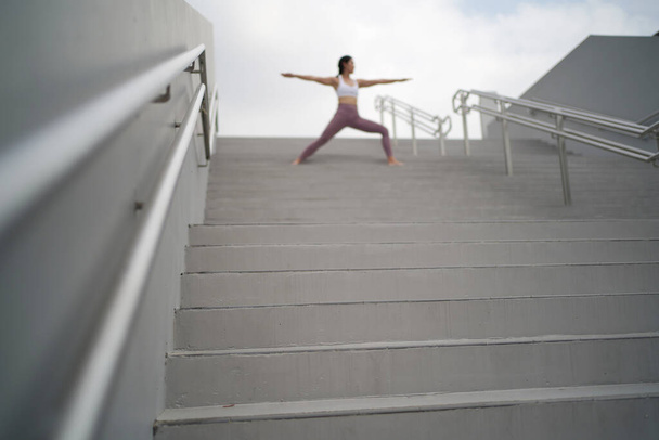 слідуючи тенденції йоги на відкритих просторах, азійська китайська пані робить йогу на сходах. - Фото, зображення