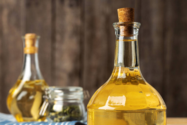 Olive oil bottle on wooden table, close up. - 写真・画像