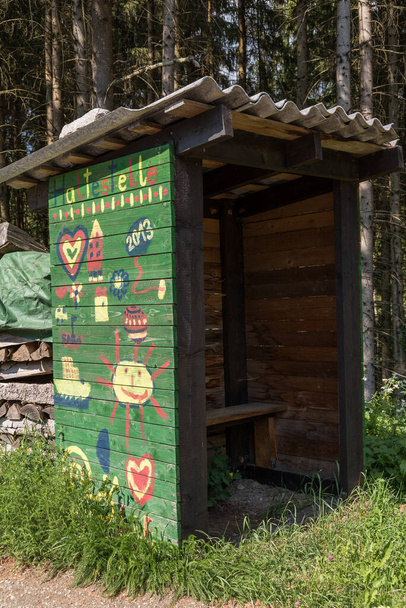 Ormanın kenarında çocuklar tarafından boyanmış otobüs durağı. Ahşap kulübe ve bekleme evi. - Fotoğraf, Görsel
