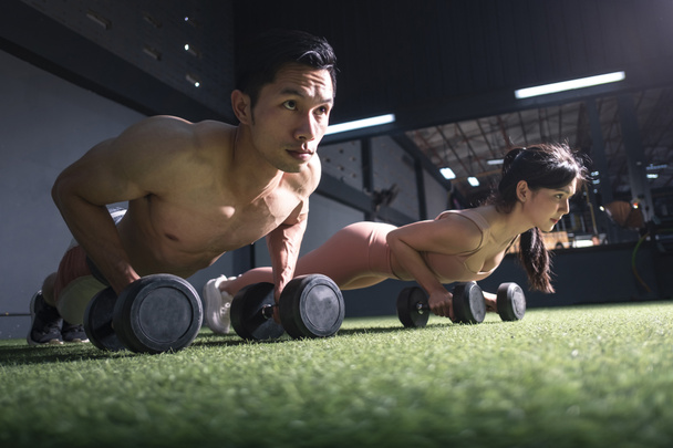 Fuerte fitness hombre y mujer haciendo ejercicio de brazo con pesas en el gimnasio
 - Foto, Imagen