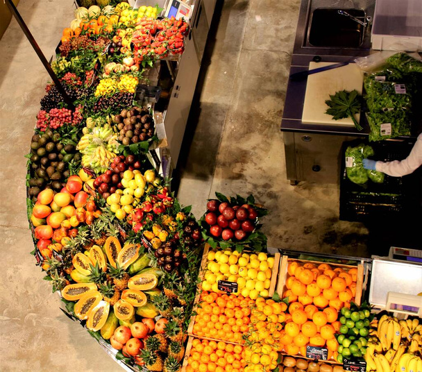 Yukarıdan kapalı bir meyve ve sebze pazarında görülen farklı meyve çeşitlerinden oluşan bir serginin canlandırıcı görüntüsü - Fotoğraf, Görsel