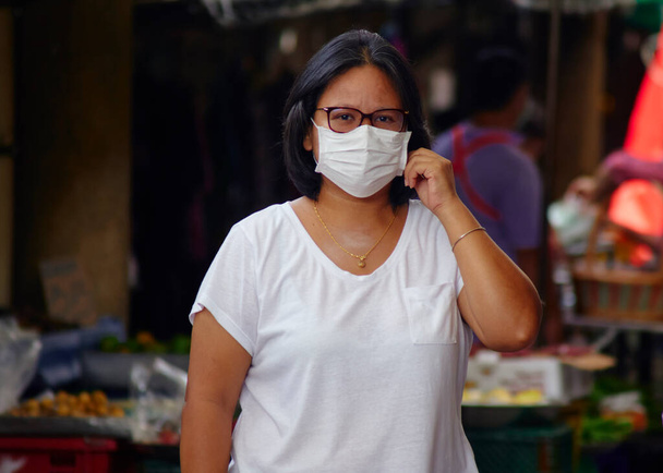 Menschenmenge mit asiatischen Frauen in Masken zum Schutz vor Viren auf belebten Marktstraßen zum Schutz vor Coronaviren - Foto, Bild