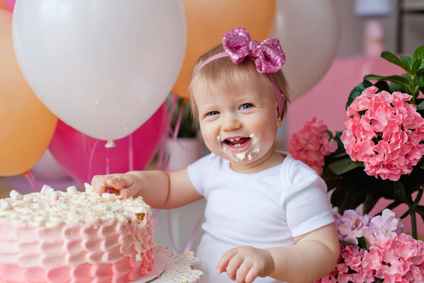 klein meisje op de tafel met een verjaardagstaart en ballonnen - Foto, afbeelding