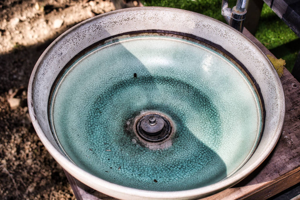 Deze unieke foto toont een oude groene keramische waskom die is verweerd door de zon en de verf is al gebarsten. - Foto, afbeelding