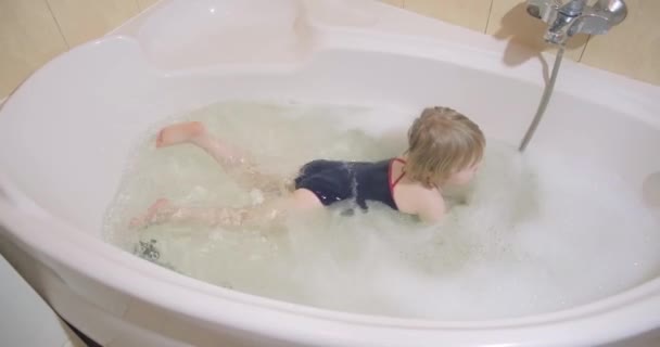 Pretty little girl takes a bath with bath foam in swimwear. - Footage, Video