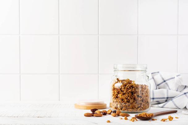 Oat granola with nuts and dried fruits to prepare a healthy breakfast on a bright kitchen table. Scandinavian white style. Selective focus. - Фото, зображення