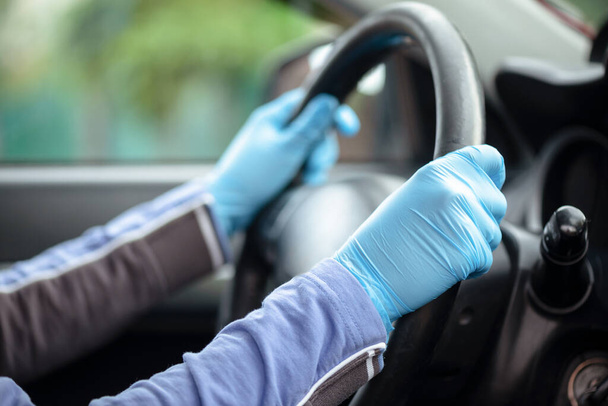 Woman is driving a car in the medical gloves close up. - Foto, Bild