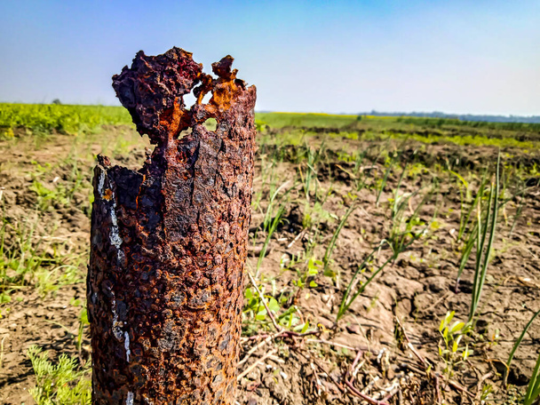 viejo tubo oxidado y tierras de cultivo en la parte posterior
 - Foto, imagen