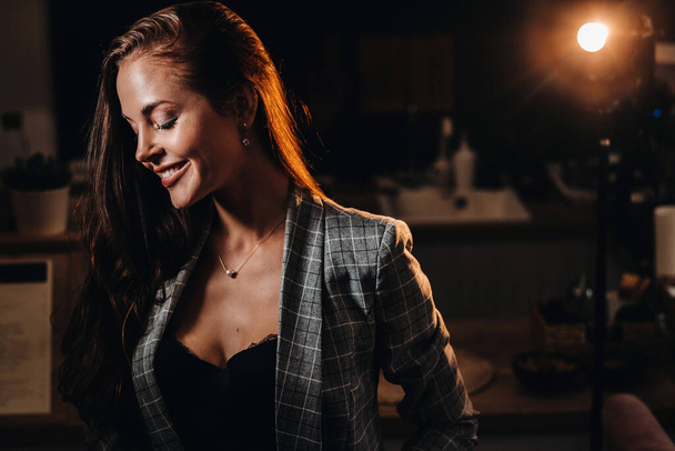 Retrato de una joven europea con el pelo largo en una cafetería a la luz de la noche, una chica alta en una chaqueta con el pelo largo en un café
. - Foto, imagen
