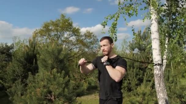 Strength training concept. Strong man doing exercises using rubber, bodybuilder workout with rubber outdoors. - Footage, Video