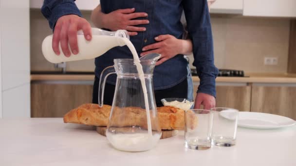 Een man giet melk in een karaf op de keukentafel. - Video