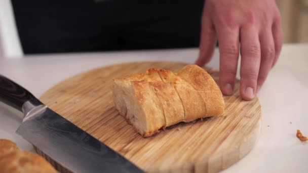 Een man legt gesneden stokbrood stukken op een witte plaat. - Video
