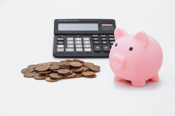 Różowa świnka lub moneta bank lub piggybank lub skrzynka na pieniądze, monety i kalkulator - koncepcja finansów i oszczędności na białym tle - Zdjęcie, obraz
