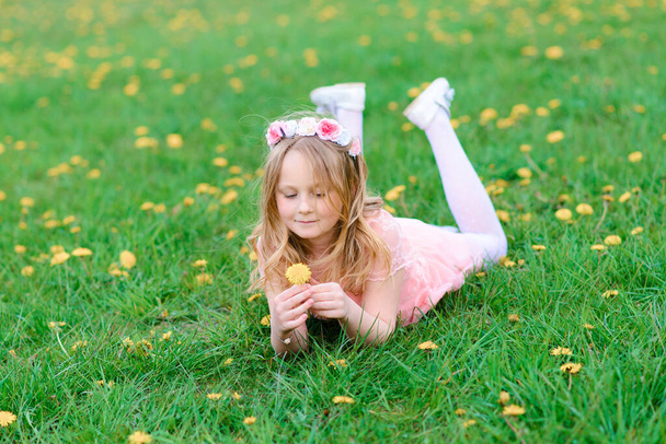 Όμορφο κορίτσι χαμογελά και παίζει στα λουλούδια του κήπου, ανθισμένα δέντρα, κεράσι. - Φωτογραφία, εικόνα