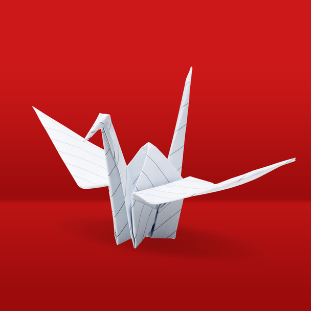 Origami crane on red background - 写真・画像