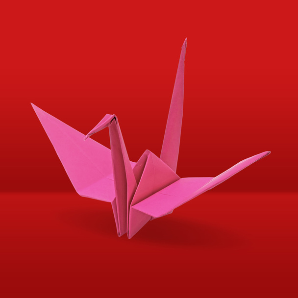 Origami crane on red background - Foto, afbeelding