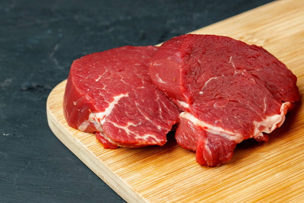 Slice of raw beef fillet on wooden board - Foto, afbeelding