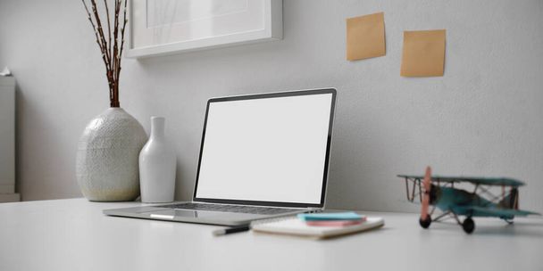 Обрезанный снимок минимального рабочего пространства с макетом ноутбука, канцелярских принадлежностей, блокнота и украшения
  - Фото, изображение