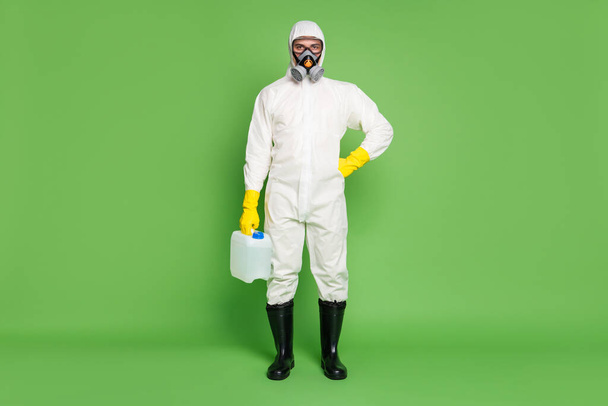 Full length body size view of his he disinfectant wearing gas mask holding in hand big bottle sanitizer sars ncov covid19 cov ebola influenza prevention isolated over green pastel color background - Foto, immagini