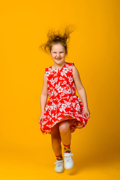Heureuses émotions insouciantes des enfants. Energique joyeuse adorable petite fille riant à la blague sur fond jaune en studio. - Photo, image