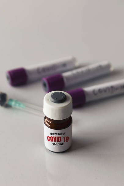 ソフトフォーカスのコロナウイルス(COVID-19)に対するクローズアップワクチンで、背景に光を当てます - 写真・画像