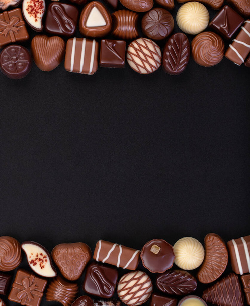 chocolade snoep op zwarte tafel met kopieerruimte, zoet eten achtergrond. - Foto, afbeelding