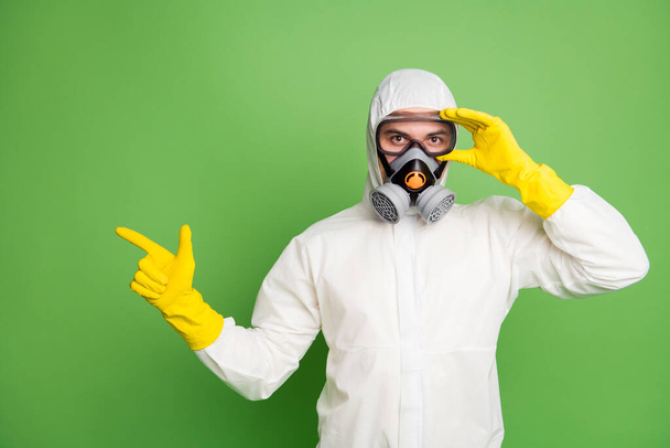 Portrait of his he nice confident professional disinfectant wearing touching fixing gas mask showing copy space quarantine restrictions news isolated over green pastel color background - Valokuva, kuva