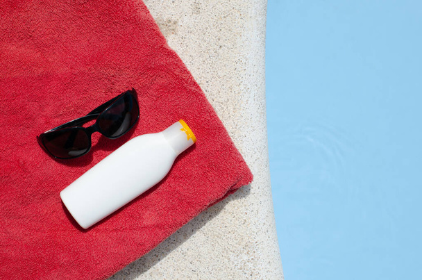 Летняя концепция с бассейном, полотенцем и кремом для загара
 - Фото, изображение
