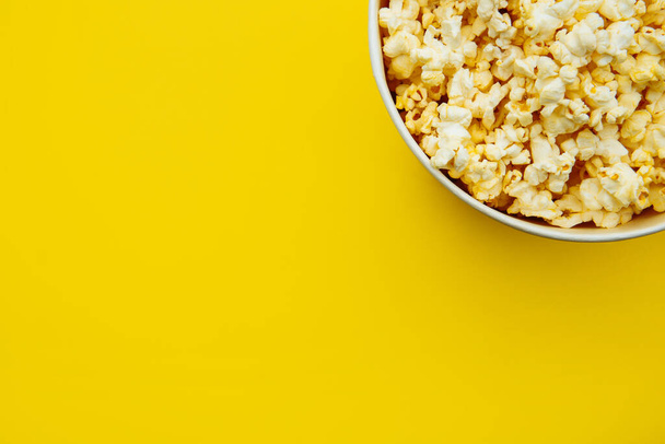 Popcorn viewed from above on yellow background. Flat lay of pop corn bowl. Top view - Foto, imagen
