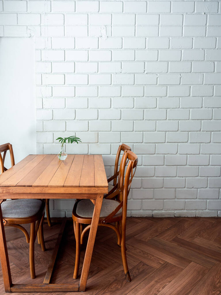 Wooden dining table and four chairs with green leaf in glass vase on white wall background in restaurant with copy space, vertical style. - Foto, afbeelding