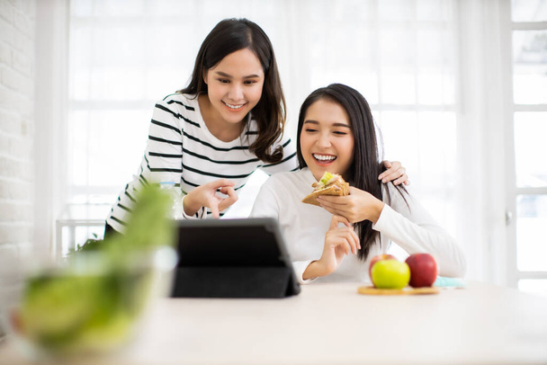 Online Group Video Call Conference of Work Team from Home Office.Smiling young asian woman  sit at home speaking.online with internet .friend work from home  and eat breakfast together. - Fotó, kép