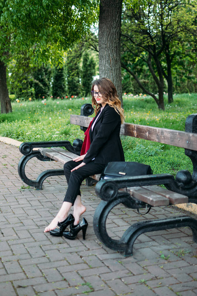 Υπερκόπωση, άγχος, ελευθερία, έννοια τερματισμού της απασχόλησης. Ξυπόλητη κουρασμένη γυναίκα κάθεται σε ένα παγκάκι του πάρκου και απολαμβάνει χαλάρωση. - Φωτογραφία, εικόνα