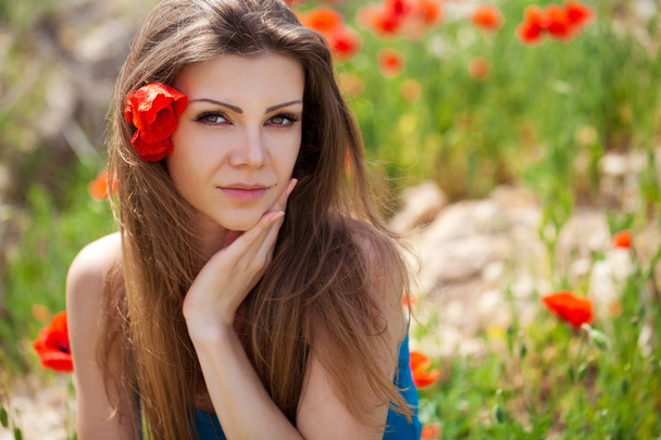 Portrait of cheerful woman outdoor with red poppy flowers in her hands - Foto, imagen