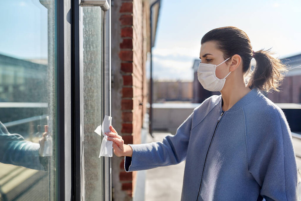 woman in mask cleaning door handle with wet wipe - Photo, image