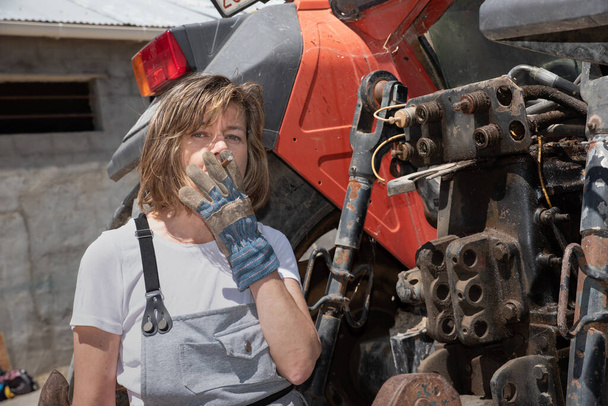 Mujer mecánica reparando un tractor al aire libre
 - Foto, Imagen
