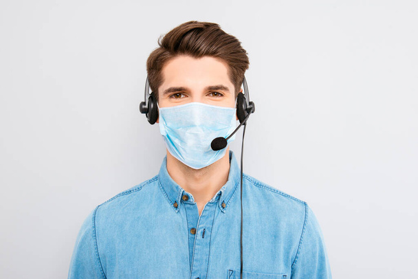 Portrait of young man worker of call center assistance wear medical mask on face and headset with microphone help other people isolated on gray background, stop pandemic of corona virus concept - Zdjęcie, obraz