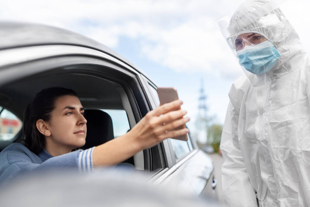 woman in car showing phohe to healthcare worker - Foto, Imagen