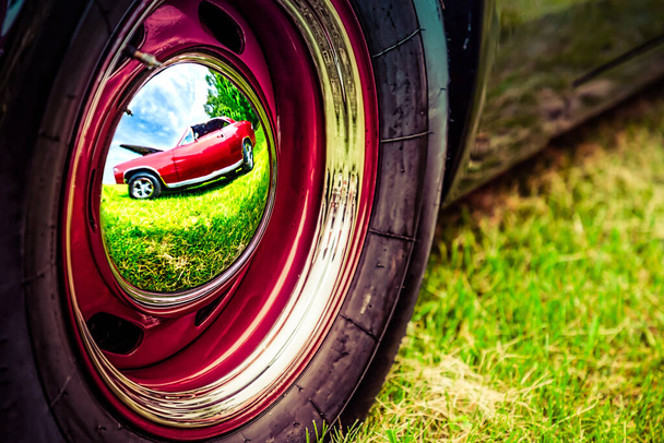 Klassinen amerikkalainen auto heijastaa toista vintage-autoa hubcap-korkistaan autonäyttelyssä
. - Valokuva, kuva