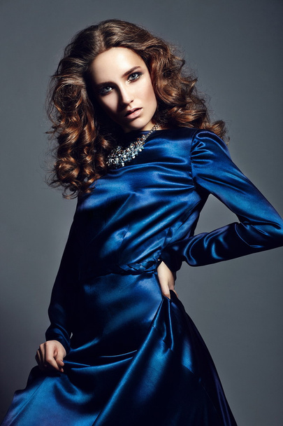 High fashion look.glamor portrait of beautiful sexy stylish brunette Caucasian young woman model with bright makeup, with healthy curly hair in bright blue dress in studio - Fotografie, Obrázek