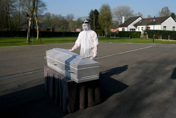 A Mortuary worker stands next to the body of a victim of the coronavirus disease inside a coffin at funeral home  in Charleroi, Belgium, on April 9, 2020 - Foto, Bild
