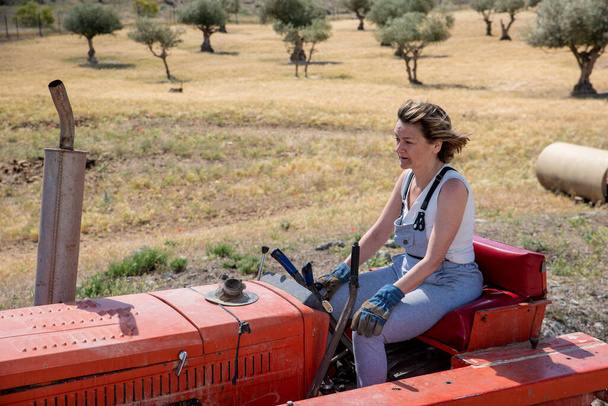 Bäuerin fährt Traktor auf ihrem Hof - Foto, Bild